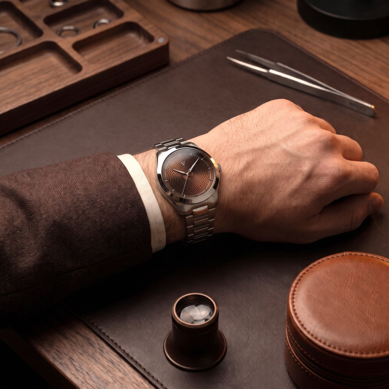 Man in a brown suit wearing the VALUSIS Velturion brown guilloché dial watch with steel bracelet at a watchmaker's desk